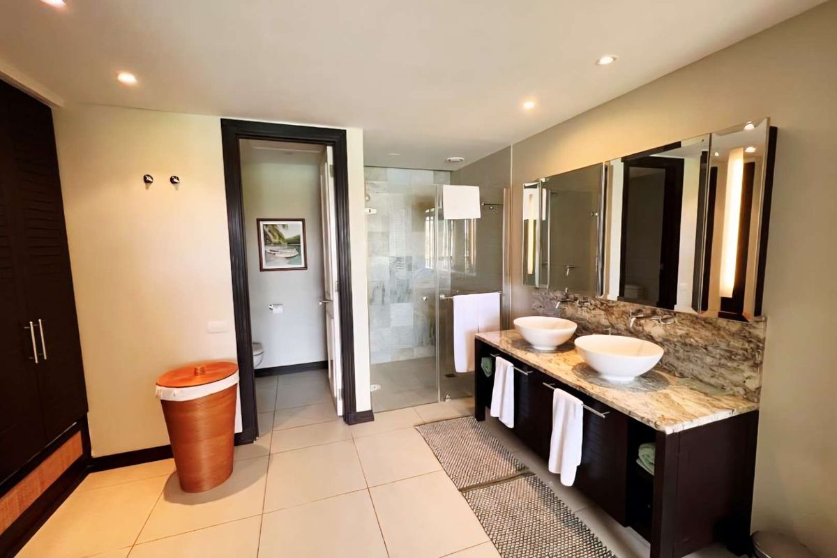 Modern bathroom featuring a double vanity with stone countertop, vessel sinks, large mirrors, and a separate glass-enclosed shower area.