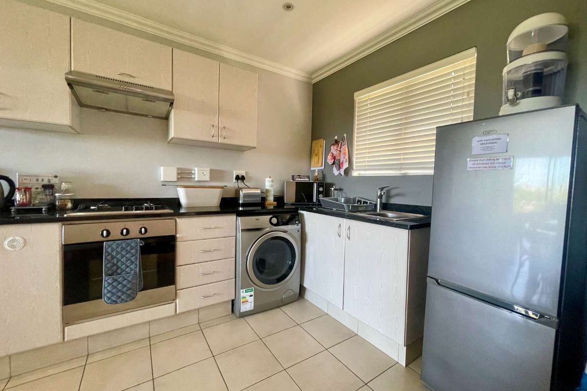 A functional kitchen featuring built-in cabinetry, a gas hob, an electric oven, and tiled flooring with a neutral color scheme.