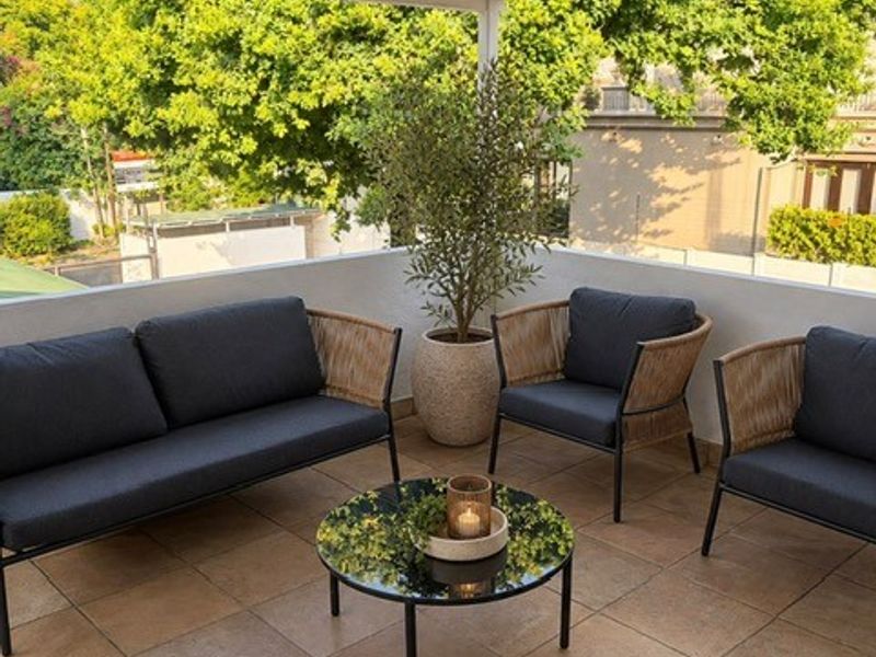 A covered balcony featuring tiled flooring and a corrugated metal roof, providing a pleasant outdoor seating area.