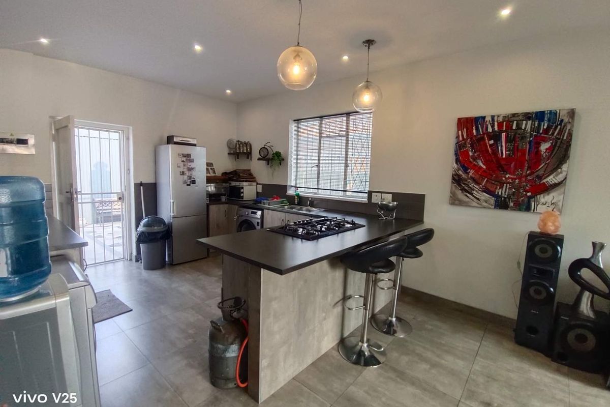 A functional kitchen featuring a central island with a built-in gas hob, tiled flooring, and direct access to an outdoor area.