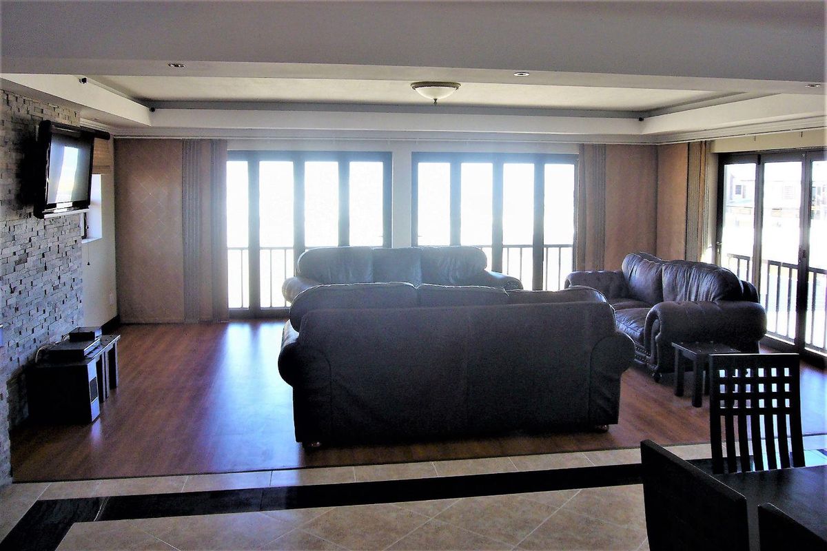 Spacious living area featuring wood-look flooring, a stone-clad feature wall, and large glass sliding doors providing ample natural light and access to the balcony.