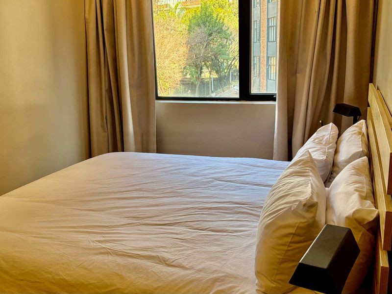 A cozy bedroom featuring a window with natural light and neutral wall finishes.