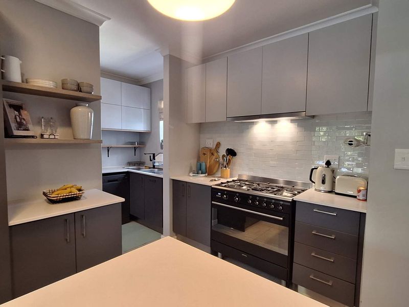 Modern kitchen featuring sleek grey cabinetry, quartz countertops, a gas stove with extractor fan, and a stylish subway tile backsplash.