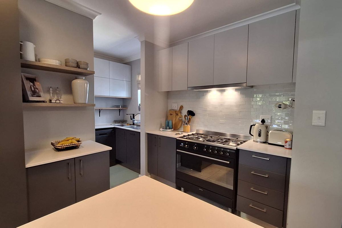 Modern kitchen featuring sleek grey cabinetry, quartz countertops, a gas stove with extractor fan, and a stylish subway tile backsplash.