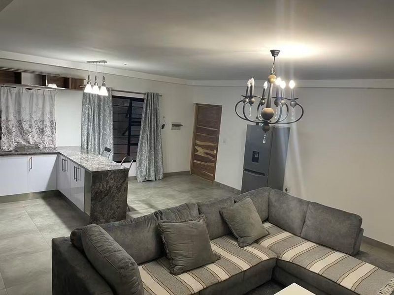 Spacious open-plan living area featuring a modern kitchen with stone countertops, tiled flooring, and elegant lighting fixtures throughout.