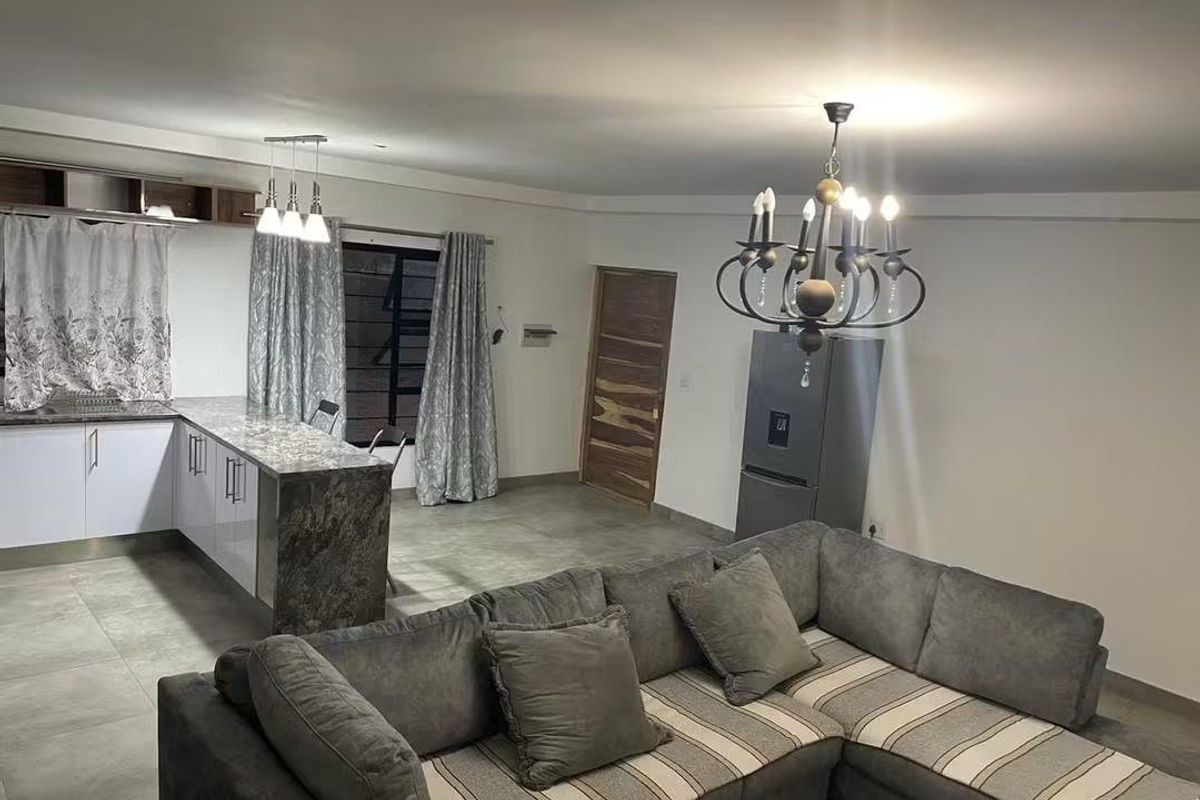 Spacious open-plan living area featuring a modern kitchen with stone countertops, tiled flooring, and elegant lighting fixtures throughout.