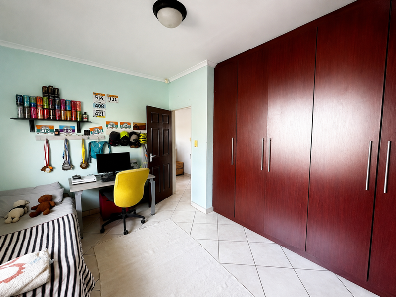 A bedroom featuring tiled flooring and extensive dark wood built-in cupboards, providing ample storage space.