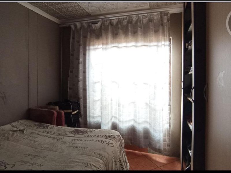 A bedroom featuring built-in wardrobe storage, tiled flooring, and decorative ceiling tiles, requiring cosmetic updates to improve the overall finish.