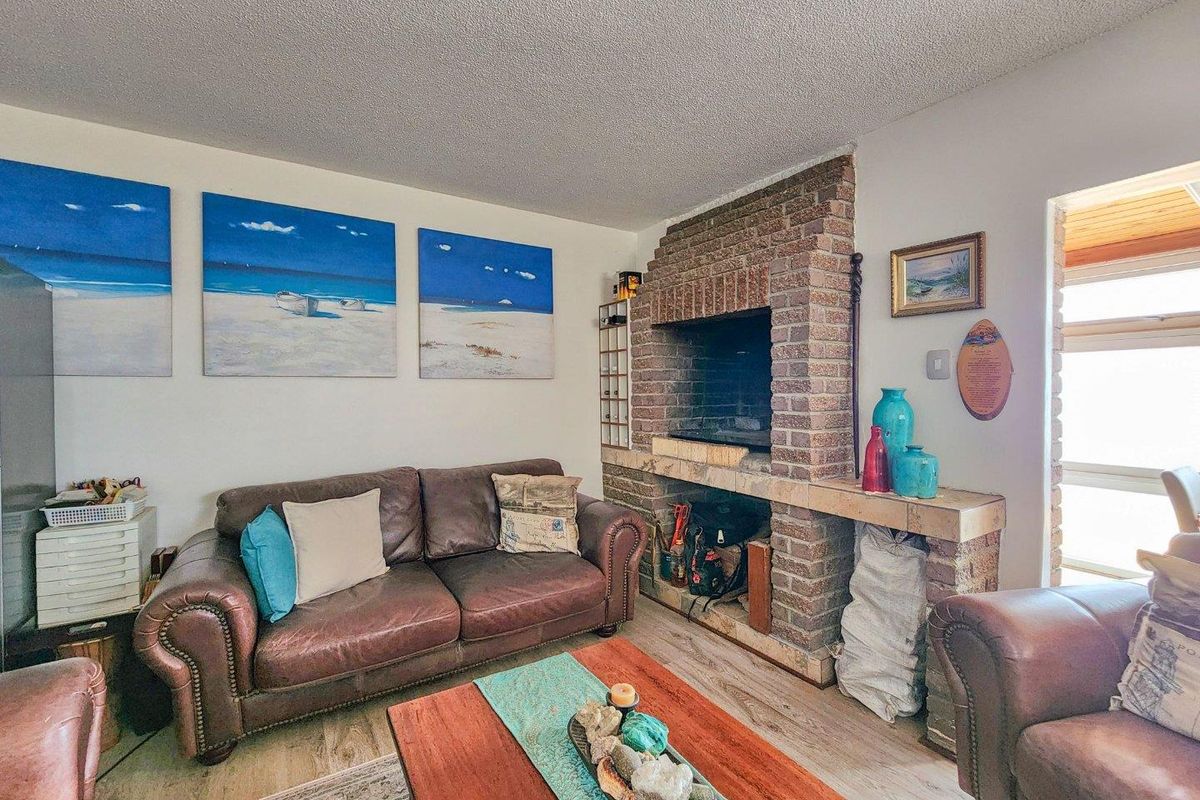 A cozy living room featuring a prominent brick fireplace and wood-look flooring, offering a warm and inviting atmosphere.