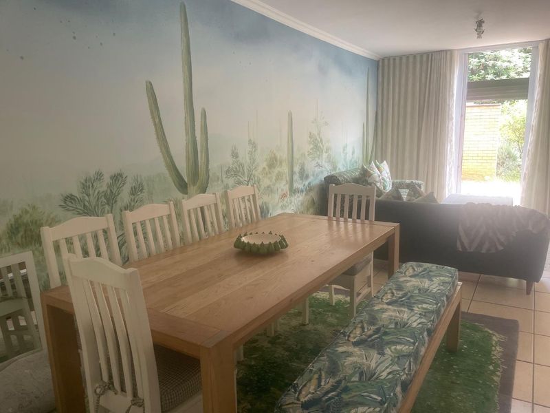 Open plan living and dining area featuring tiled flooring, a large feature wall mural, and direct access to an outdoor space via sliding glass doors.
