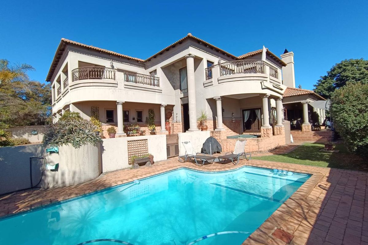 Spacious double-story residence featuring a large swimming pool, expansive patio areas, classic architectural columns, and a well-maintained rear garden.
