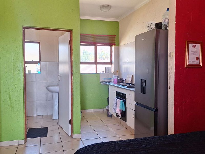 A compact kitchen area featuring tiled flooring, built-in oven and stove, and an adjacent bathroom with a pedestal sink.