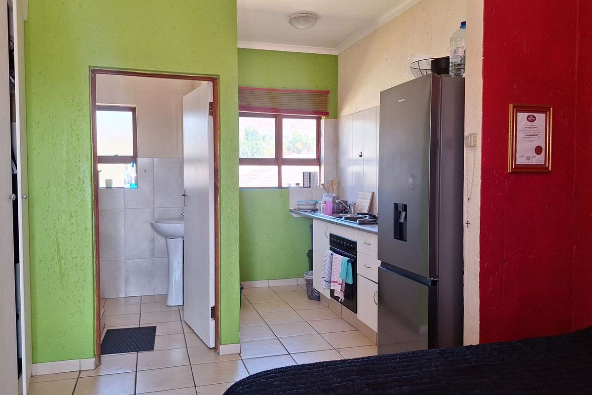A compact kitchen area featuring tiled flooring, built-in oven and stove, and an adjacent bathroom with a pedestal sink.