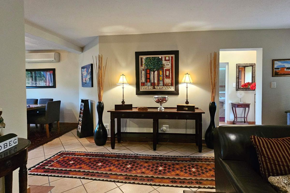 A well-maintained living area featuring tiled flooring, neutral walls, and a split-system air conditioning unit, with a clear view into the adjacent dining space.