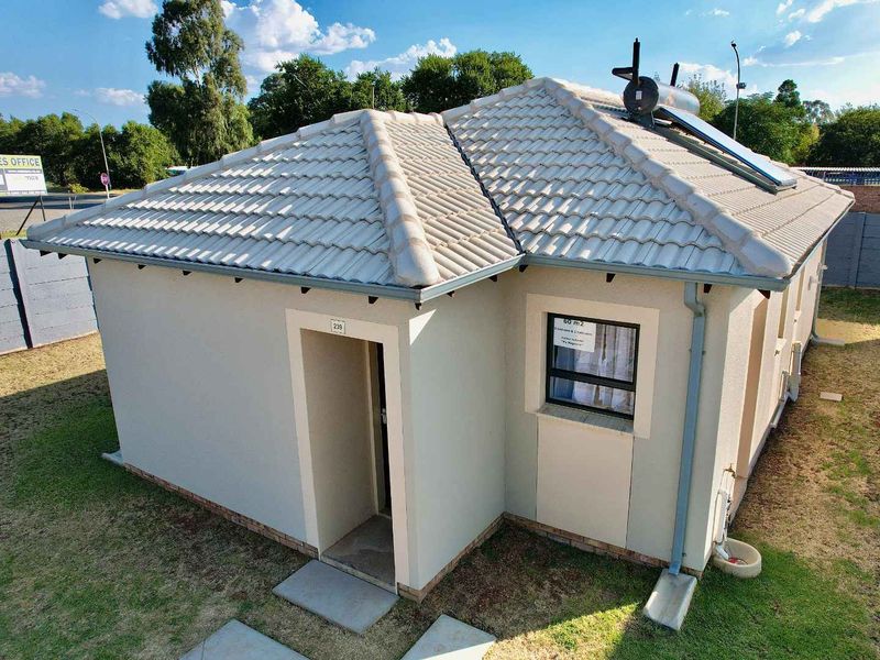 A well-maintained single-story residential house featuring a tiled roof, solar water heating system, and a clean exterior facade with a paved entrance.