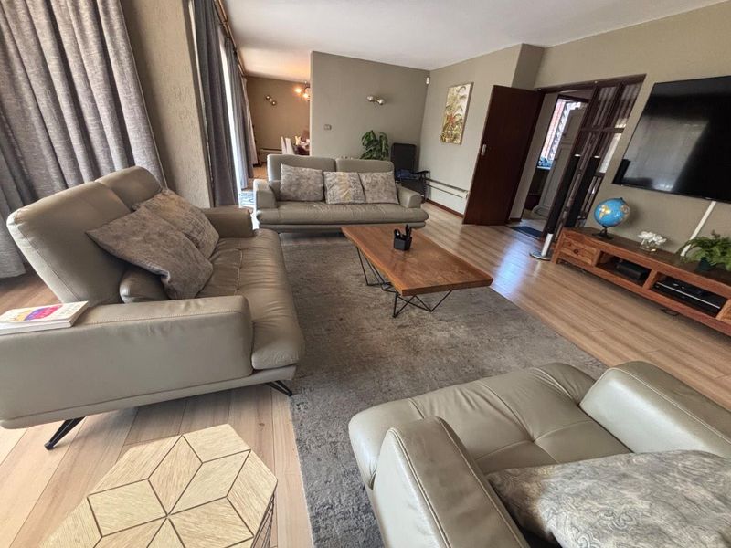 Spacious living room featuring laminate flooring, neutral wall tones, and large sliding glass doors providing natural light and access to the exterior.