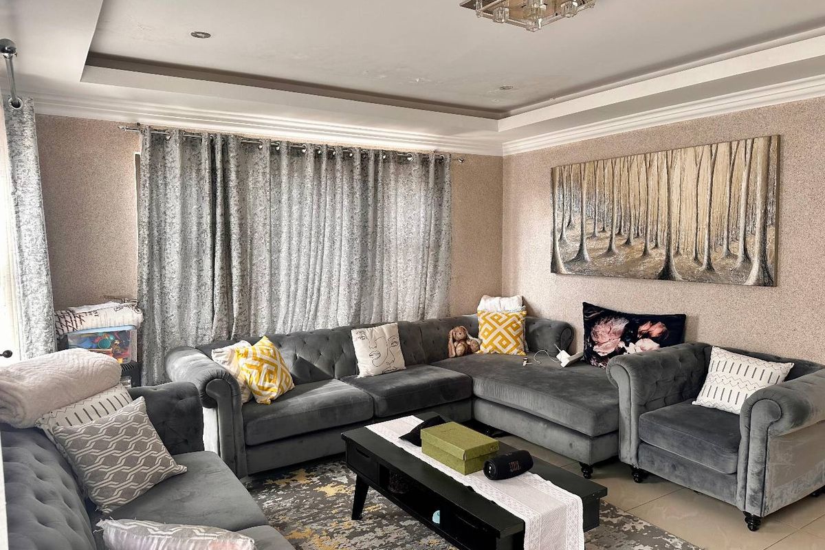 A comfortable living room featuring a tray ceiling with recessed lighting and textured wallpaper.