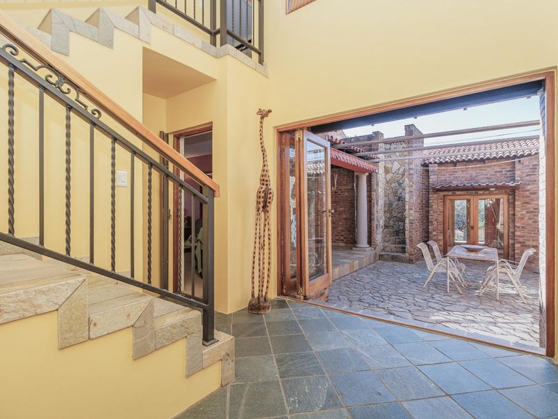 Entrance hall featuring slate flooring and a stone staircase, opening through bi-fold doors to a private stone-paved courtyard.