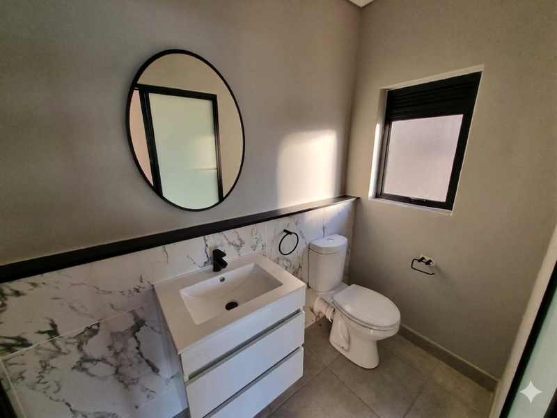 Modern bathroom featuring a sleek vanity with basin, marble-look wall tiling, and a contemporary toilet, finished with high-quality fixtures.