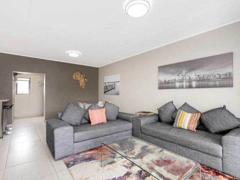 A well-lit living room featuring neutral wall tones, tiled flooring, and flush mount ceiling lights, providing a comfortable and functional living space.