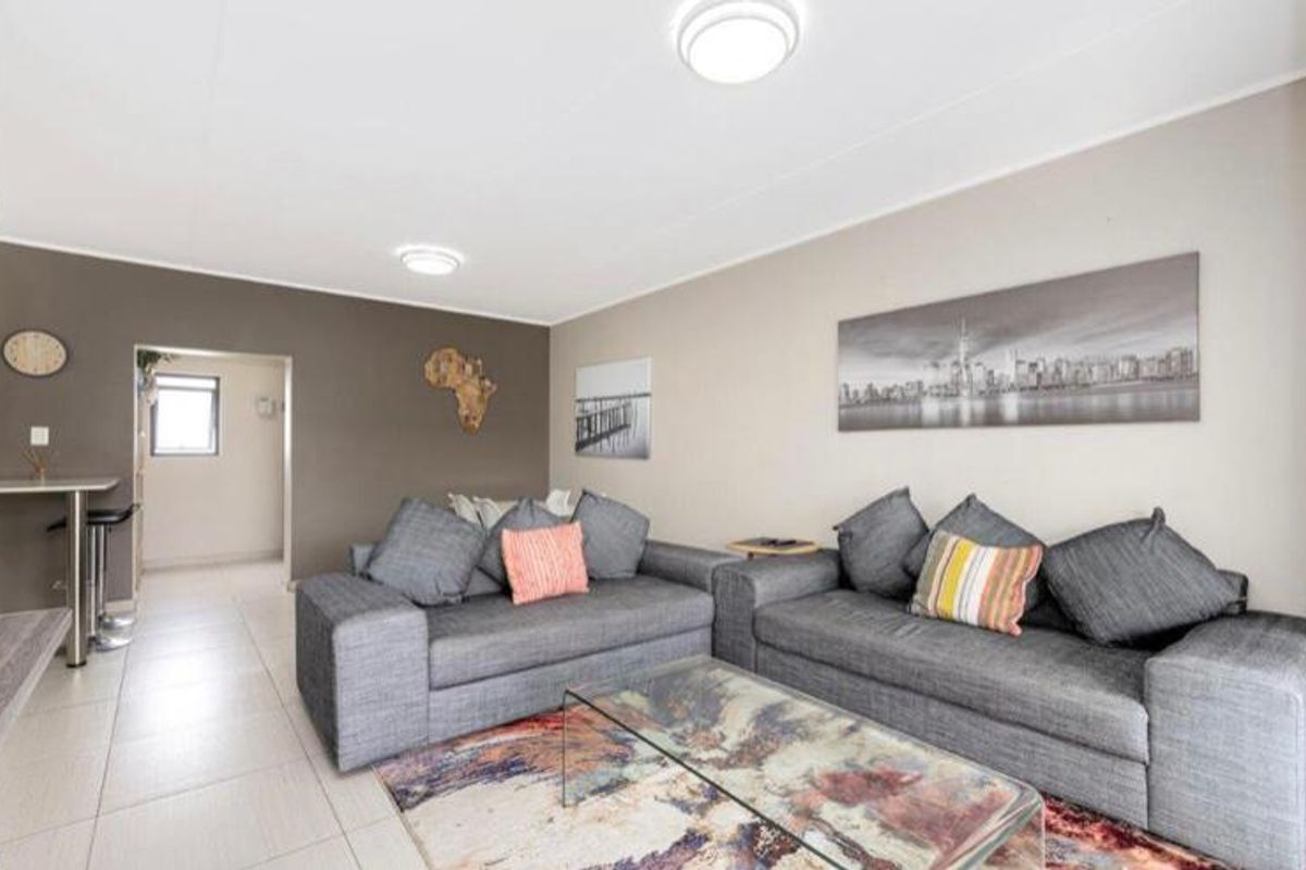 A well-lit living room featuring neutral wall tones, tiled flooring, and flush mount ceiling lights, providing a comfortable and functional living space.
