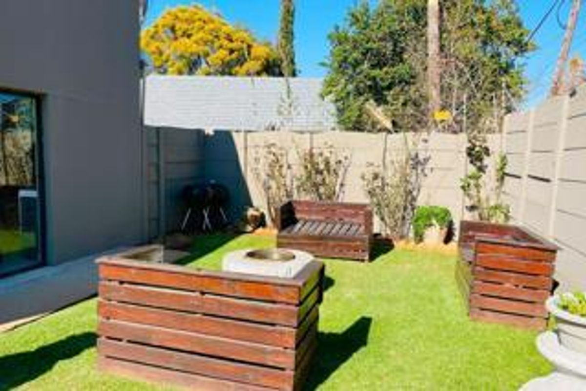 A private rear garden area featuring an artificial lawn, enclosed by a precast concrete boundary wall with direct access to the home via sliding doors.