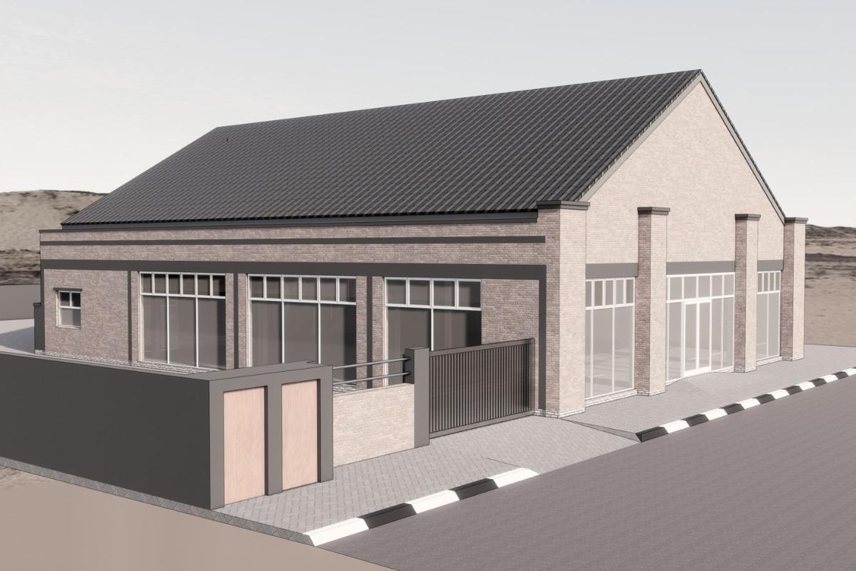 A modern commercial building featuring a pitched metal roof, brick facade, and large glass storefront windows with secure perimeter walling and gated access.