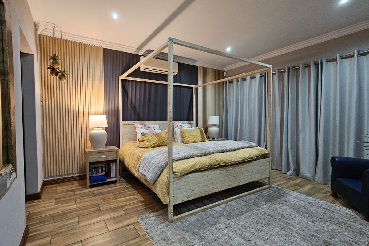 A well-appointed bedroom featuring modern timber slat wall paneling, wood-look floor tiles, and a split-system air conditioner for climate control.