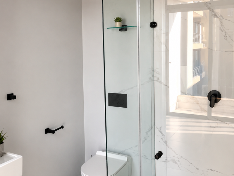 Modern bathroom featuring a wall-hung toilet, glass-enclosed shower with rain head, marble-look tiling, and contemporary black matte fixtures.