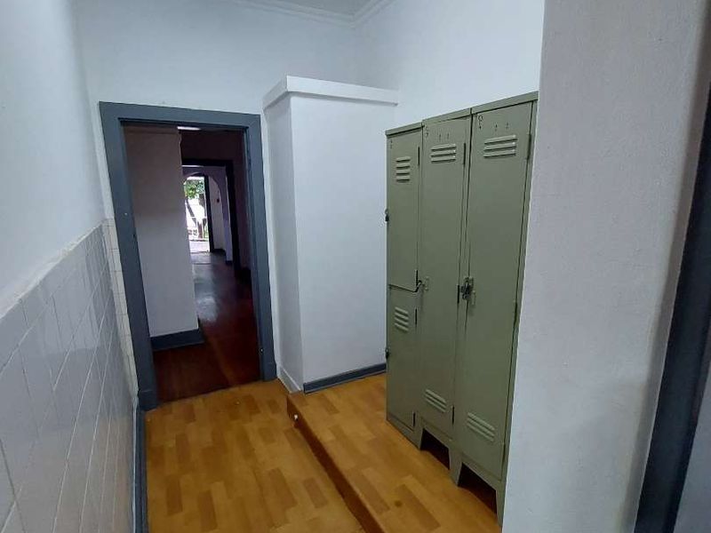 A functional hallway area featuring wooden flooring, tiled wall accents, and built-in metal storage lockers, leading through to an adjacent room.