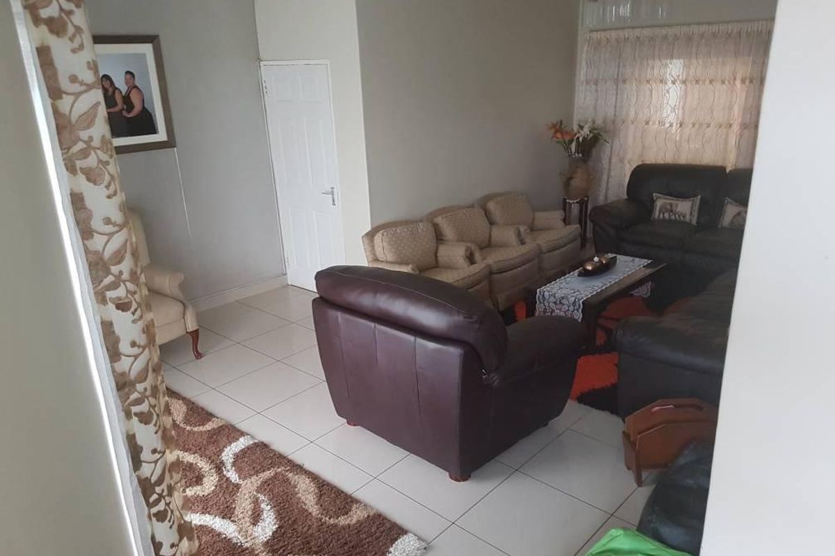 A spacious living room featuring neutral tiled flooring and a high ceiling, providing a comfortable and functional area for relaxation.