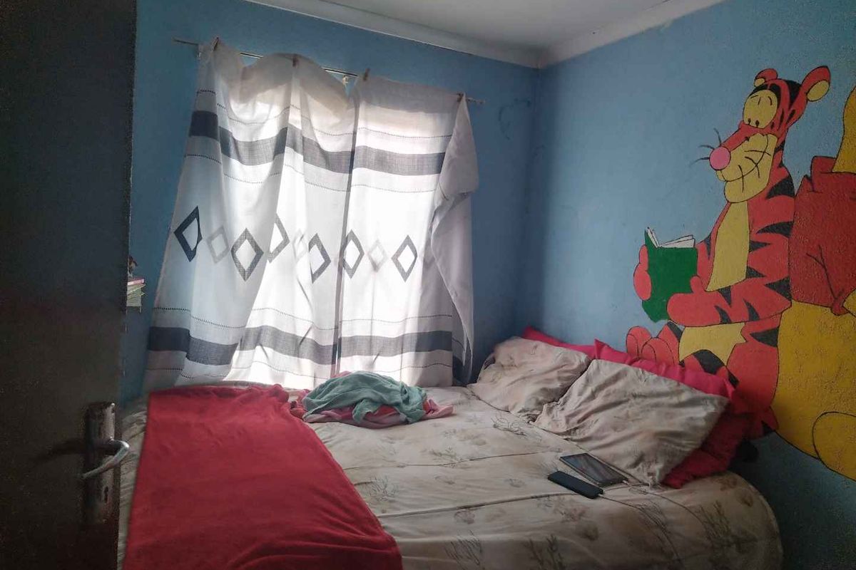 A bedroom featuring blue walls with decorative wall art, a window with curtains, and standard interior finishes.