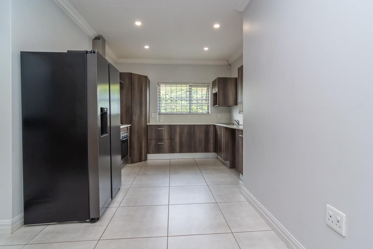 Modern kitchen featuring dark wood cabinetry, tiled flooring, recessed lighting, and a built-in oven with extractor fan.