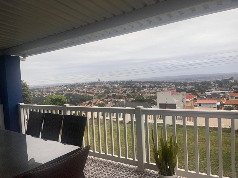 A covered patio featuring patterned floor tiles and a white railing, offering an elevated view over the surrounding residential neighborhood.
