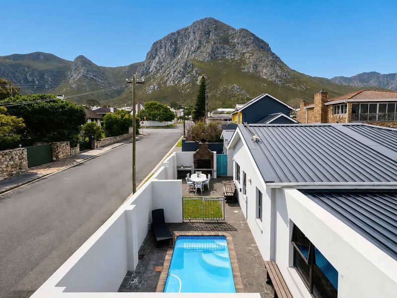 Aerial view of a property featuring a private swimming pool, paved courtyard with a built-in braai, and mountain views.