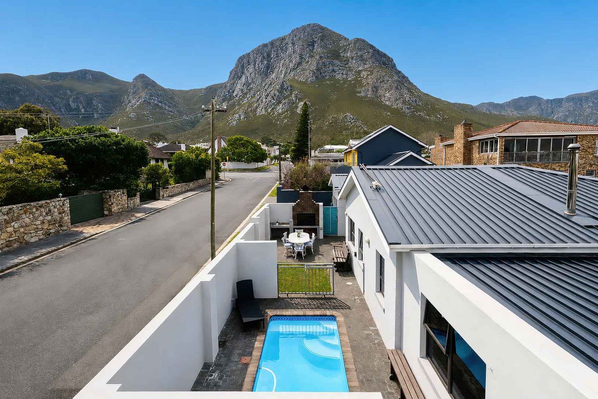 Aerial view of a property featuring a private swimming pool, paved courtyard with a built-in braai, and mountain views.
