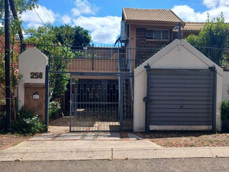Front elevation of the property featuring a secure gated entrance, roller garage door, and paved driveway access.