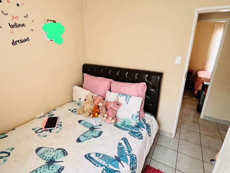 A compact bedroom featuring tiled flooring and neutral wall finishes, with a view leading into an adjacent room.