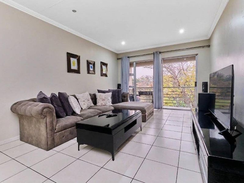 A bright living room featuring tiled flooring, recessed lighting, and a sliding glass door providing access to an outdoor balcony area.
