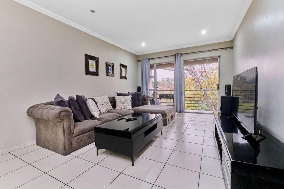 A bright living room featuring tiled flooring, recessed lighting, and a sliding glass door providing access to an outdoor balcony area.