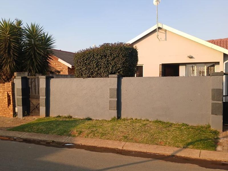 Front view of the property featuring a solid perimeter wall, metal pedestrian gate, and a tiled roof structure.