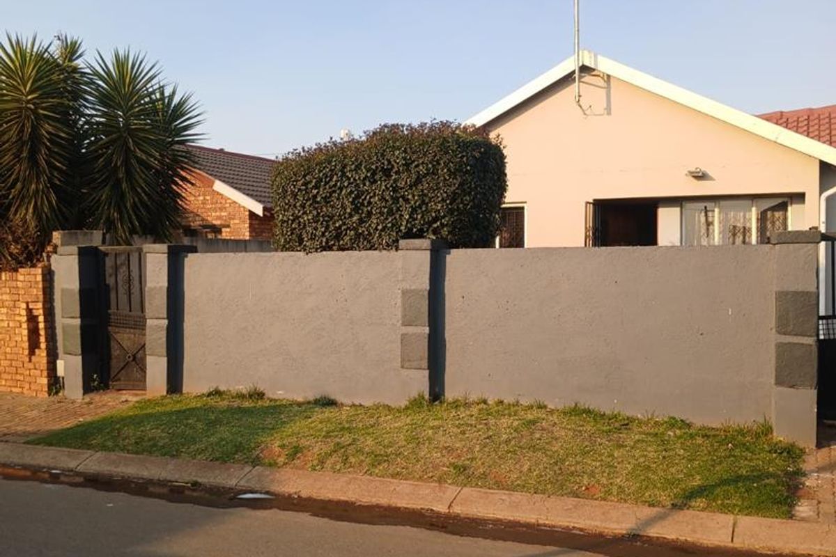Front view of the property featuring a solid perimeter wall, metal pedestrian gate, and a tiled roof structure.