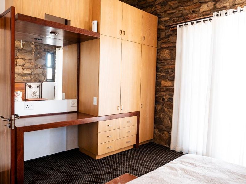 Bedroom featuring a rustic stone feature wall, extensive built-in wooden cabinetry, and a integrated vanity area with mirror.