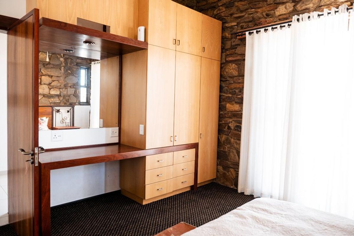 Bedroom featuring a rustic stone feature wall, extensive built-in wooden cabinetry, and a integrated vanity area with mirror.