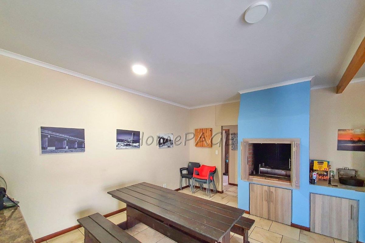 Indoor entertainment area featuring a built-in braai, tiled flooring, and direct access to adjacent rooms.