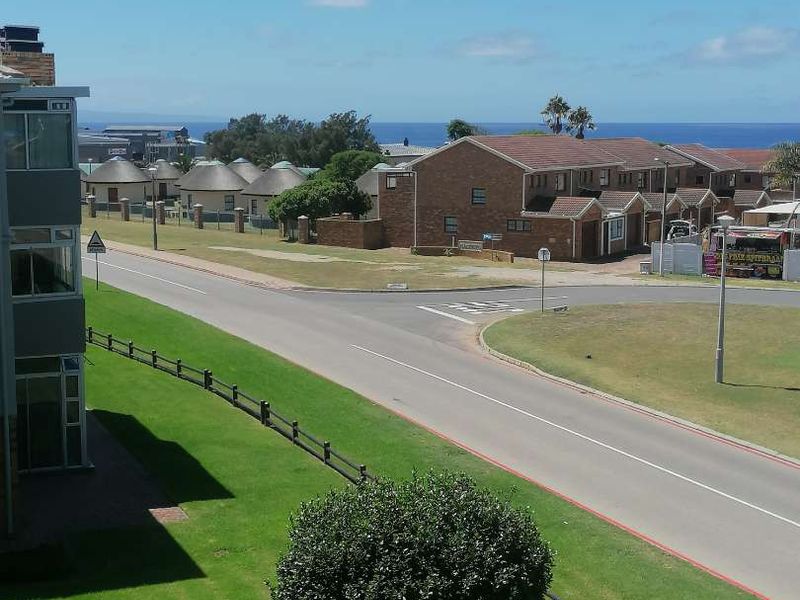 Elevated view overlooking the surrounding residential neighbourhood, street, and distant ocean horizon.