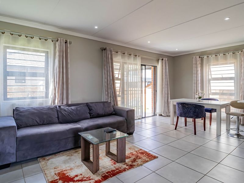 Spacious open-plan living and dining area featuring tiled flooring, recessed lighting, and direct access to an outdoor patio through sliding glass doors.
