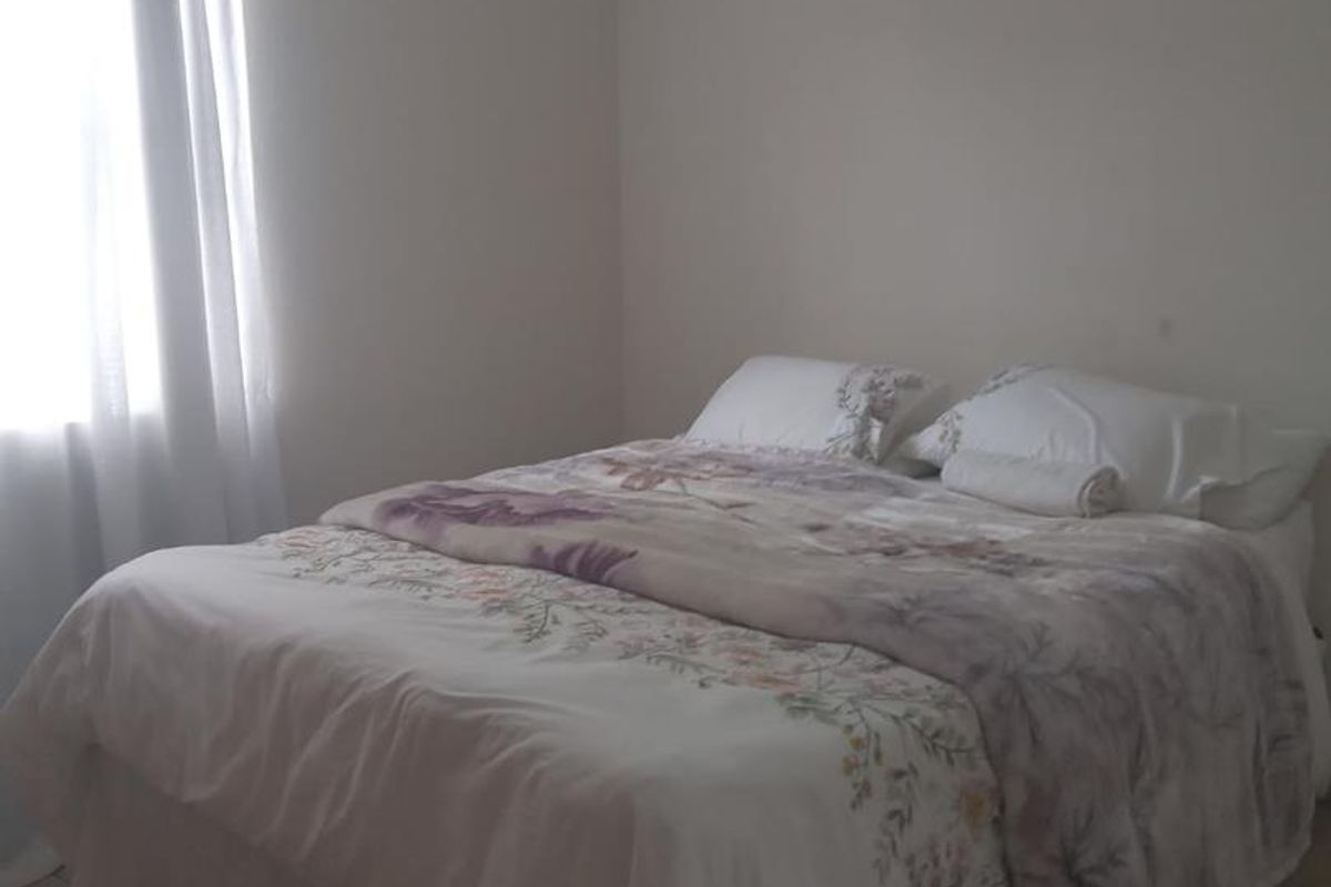 A simple bedroom featuring neutral wall finishes and tiled flooring, providing a functional and well-lit space.