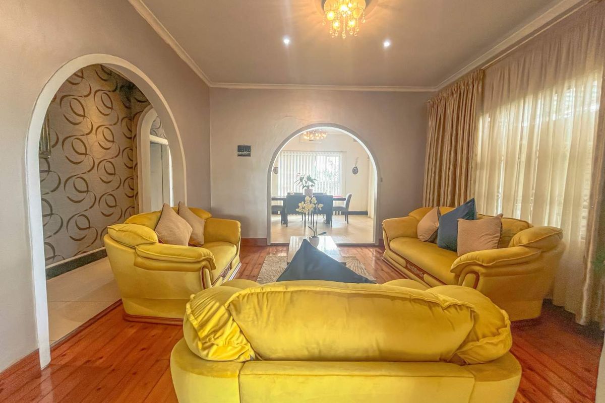 Spacious living room featuring arched doorways, polished timber flooring, and decorative wall accents, leading through to an adjacent dining area.