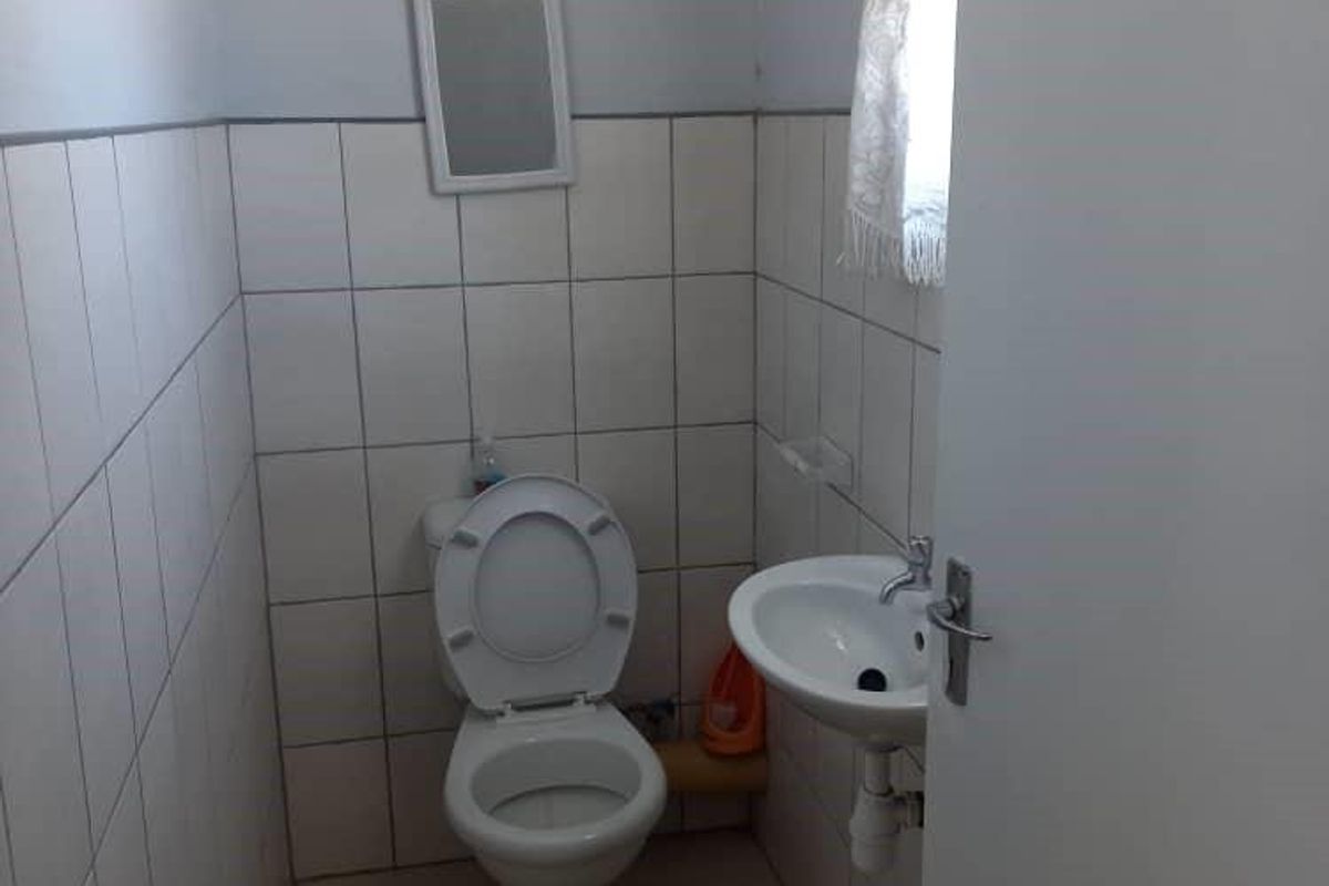 A compact guest bathroom featuring a standard toilet, wall-mounted basin, and tiled walls.